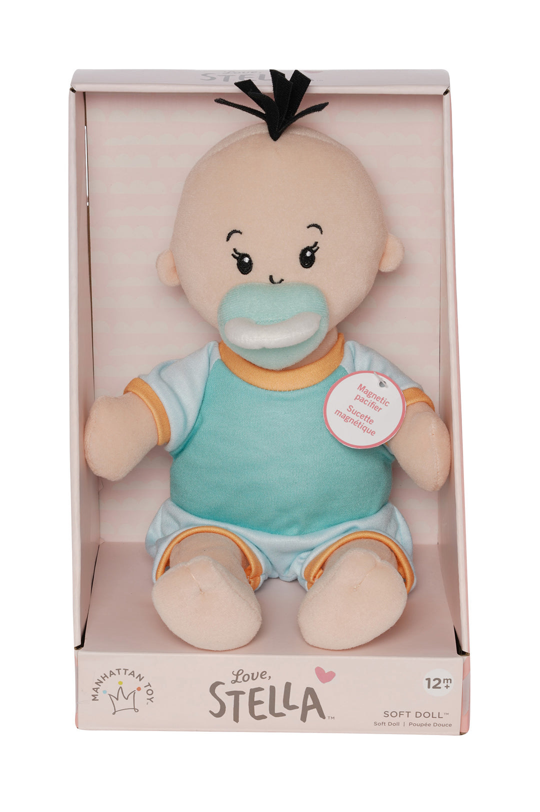 soft baby doll with peach skin and black hair wearing  a onesie with short sleeves and pants  with a magnetic pacifier in open front box packaging