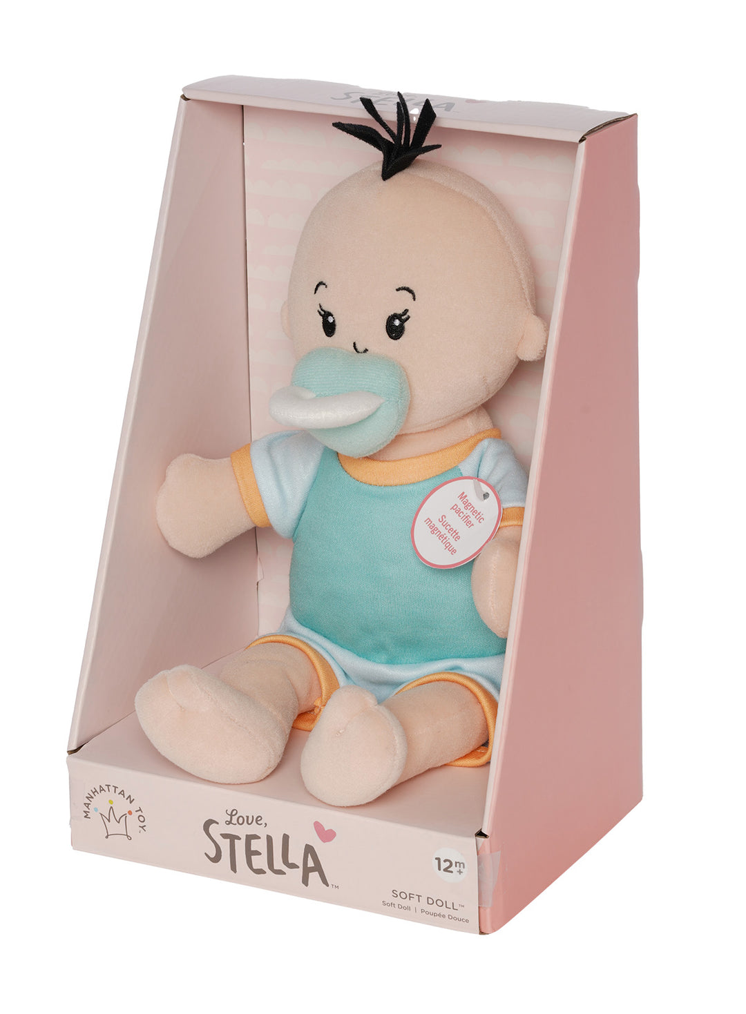 soft baby doll with peach skin and black hair wearing  a onesie with short sleeves and pants  with a magnetic pacifier in open front box packaging