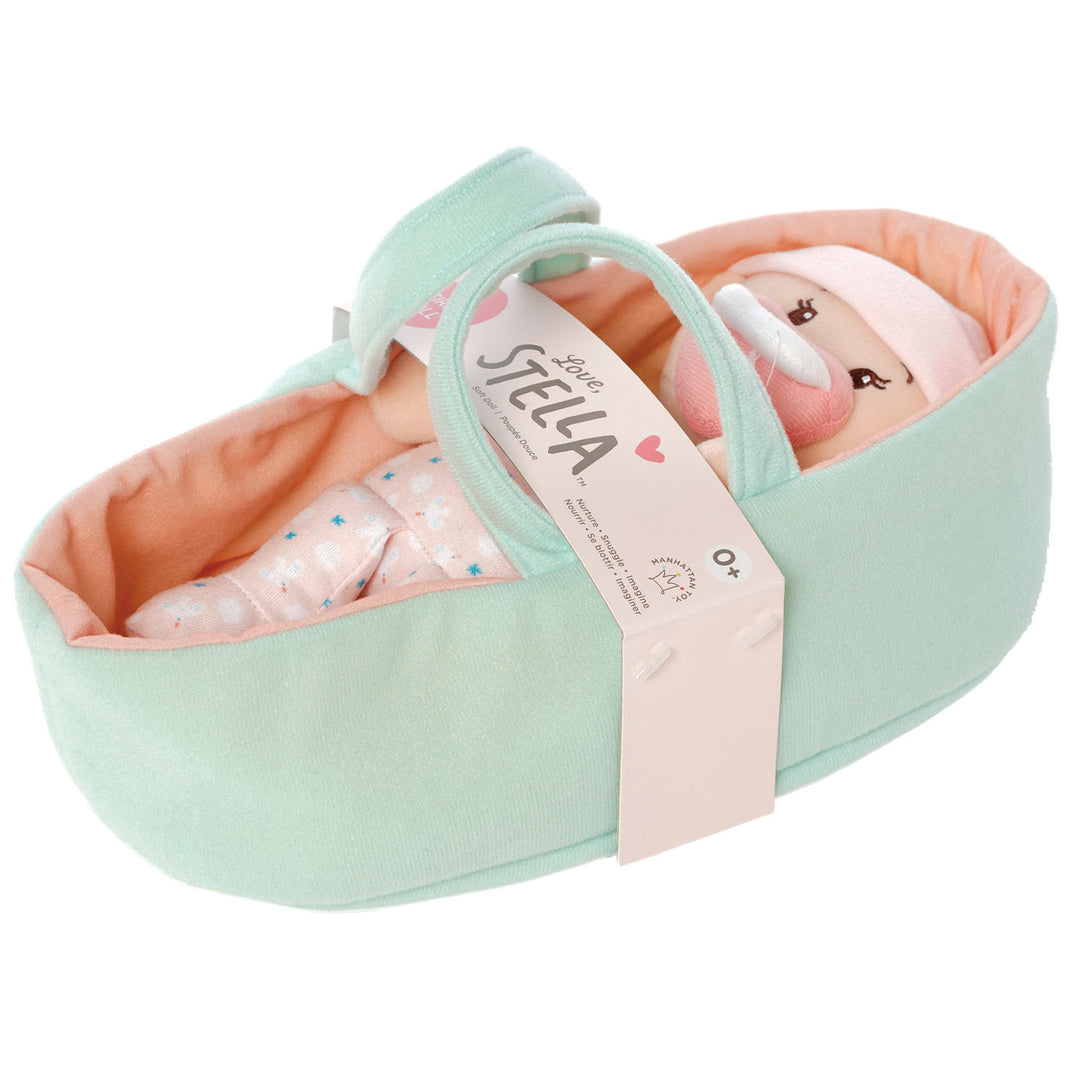 soft baby snuggle doll with peach skin with magnetic pacifier laid in a pink bassinet with belly-band packaging