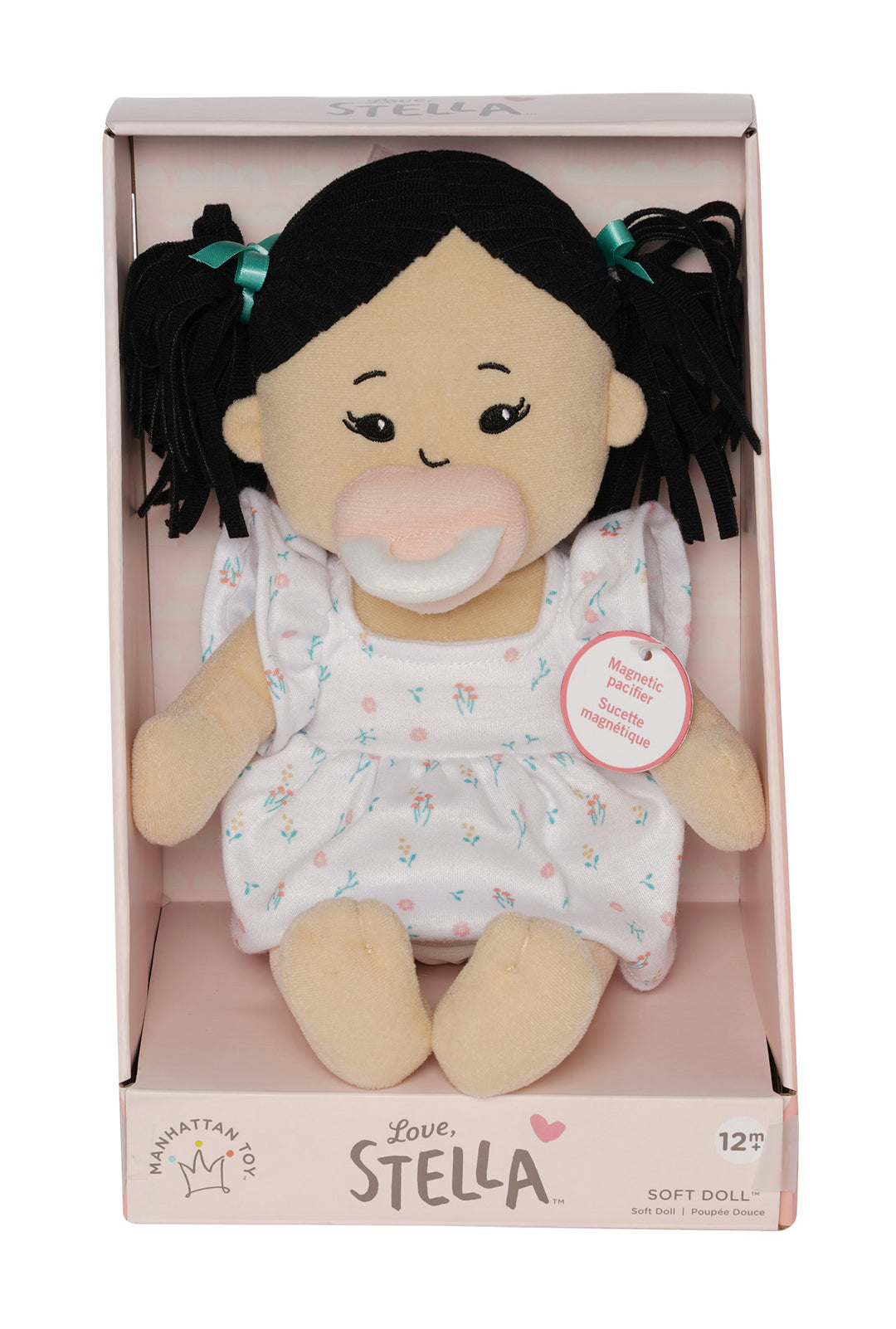 soft baby doll with light beige skin and black hair wearing a dress with a magnetic pacifier in open front box package