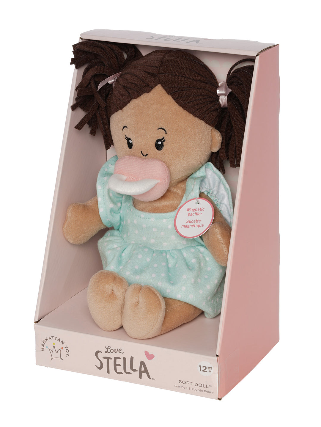 soft baby doll with beige skin and brown pigtails wearing a dress with a magnetic pacifier in open front box package