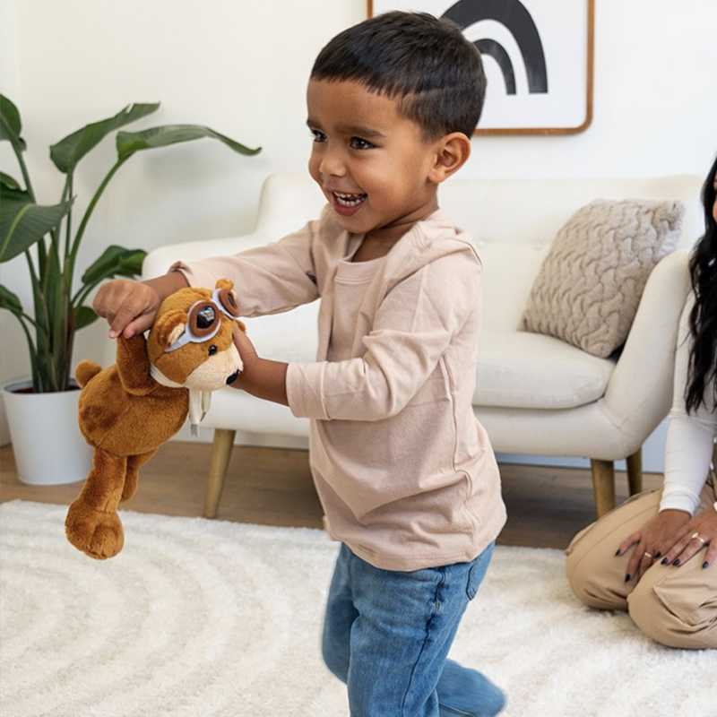 toddler boy swinging stuffed animal bear around the room