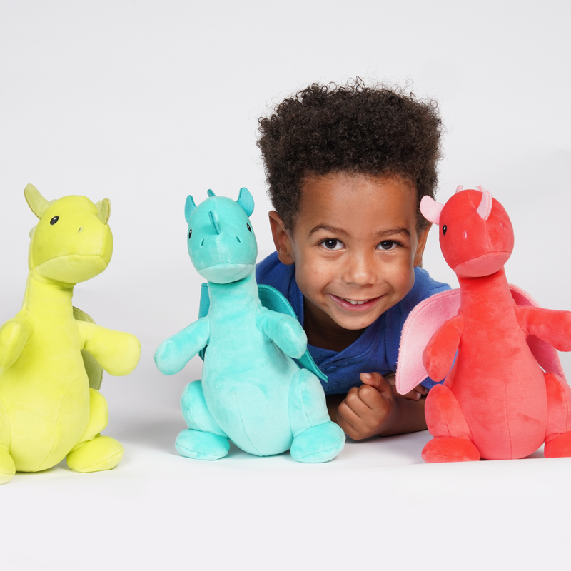 little boy smiling with three colorful plush dragons.