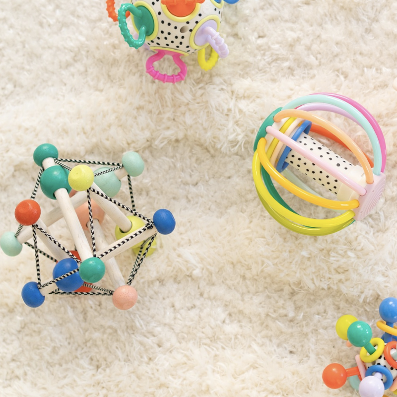 Colorful baby rattles on fuzzy rug