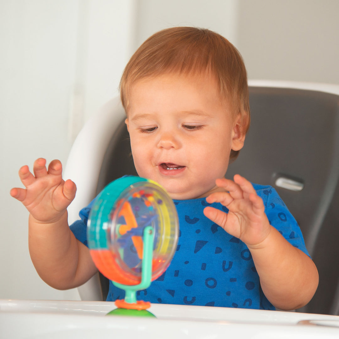 baby playing with spinner tray toy in highchair